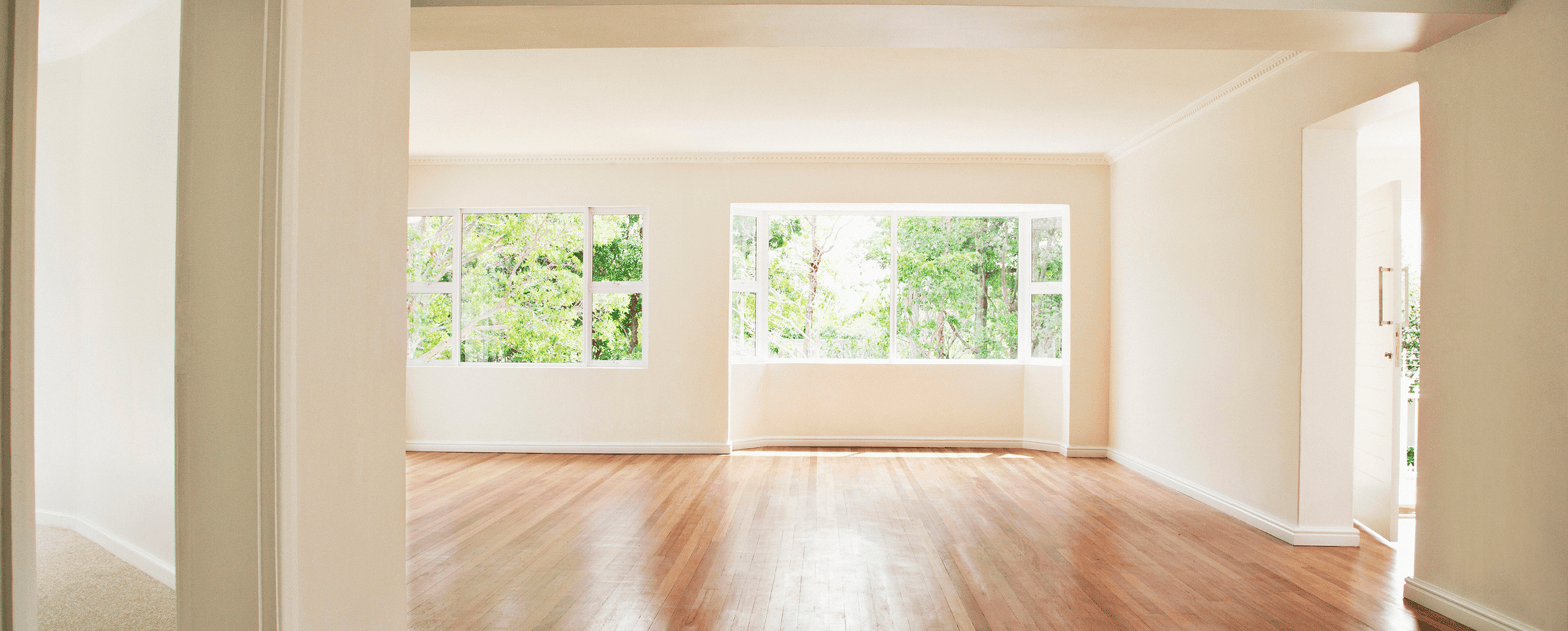 Bright empty room with wooden floor and windows.
